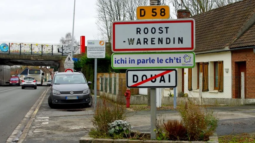 Panneaux de signalisation de la ville de Roost-Warendin avec une experssion ch'ti : "ichi in parle le ch'ti"